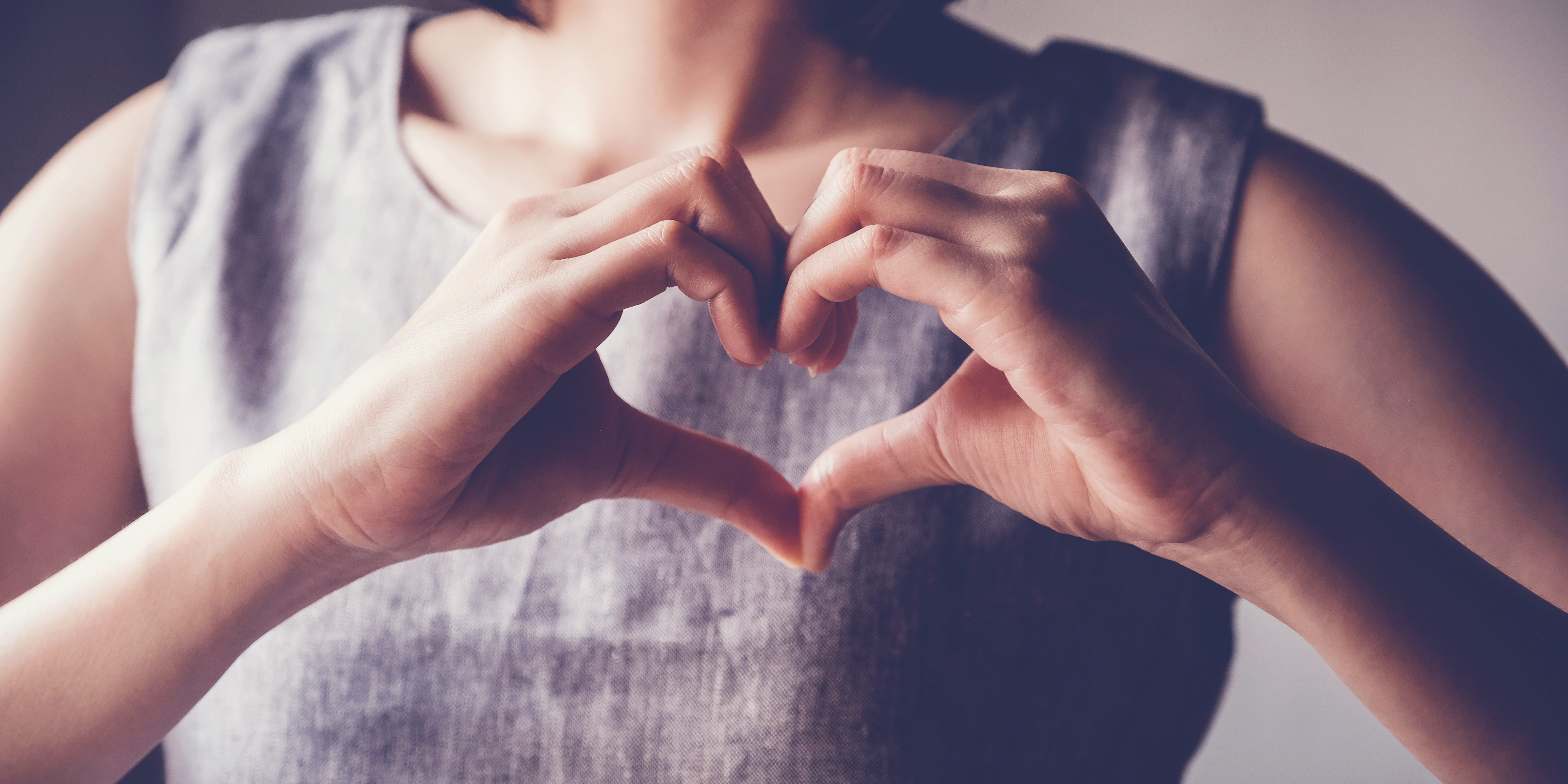 Amore e solidarietà – mani a forma di cuore Donna che forma un cuore con le mani davanti al petto, simbolo di amore e solidarietà
